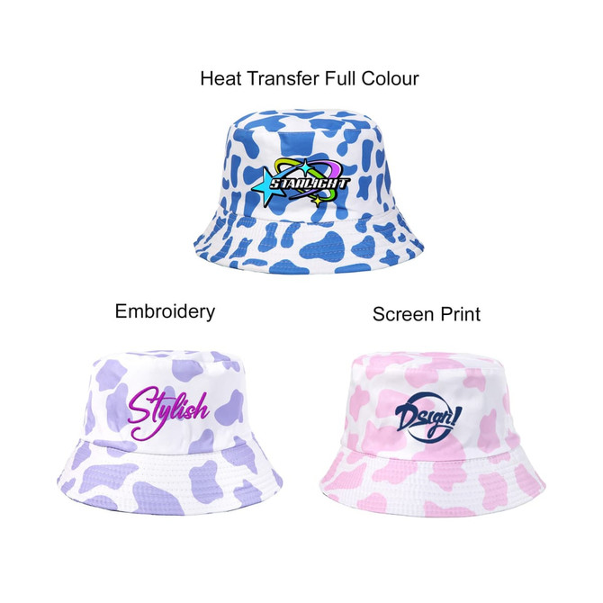 A cow print bucket hat featuring blue and white designs, with branding and embroidered text in various styles.