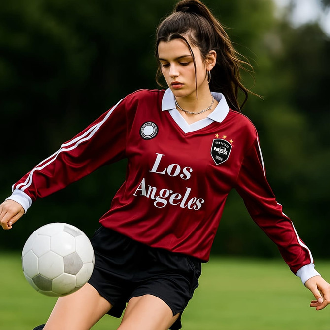 A unisex polo football jersey in maroon with white stripes, featuring a logo and text. The jersey is worn with black shorts.