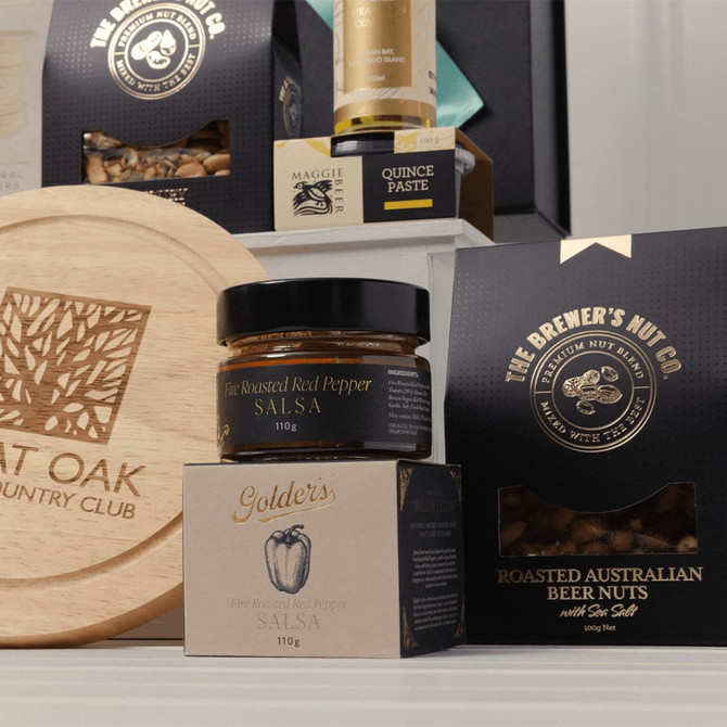 A wooden platter, jars of salsa, beer nuts in a box, and a bottle of paste in a promotional product set.