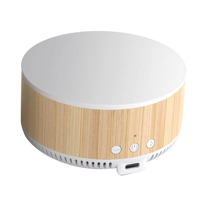 A round wireless charging speaker in a natural wood finish with a white top and control buttons on the front.