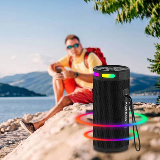 A black wireless speaker with colourful LED lights, positioned by a lake with a person in the background.