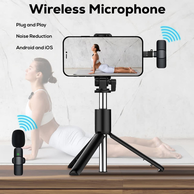 A wireless microphone with a black design, positioned on a tripod, next to a smartphone displaying a person in a yoga pose.