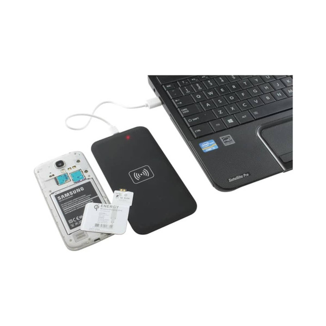 A wireless charger in black connected to a laptop, with a smartphone's back cover removed nearby.