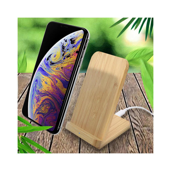 A wooden bamboo wireless charger stands upright beside a smartphone, set against a leafy background.