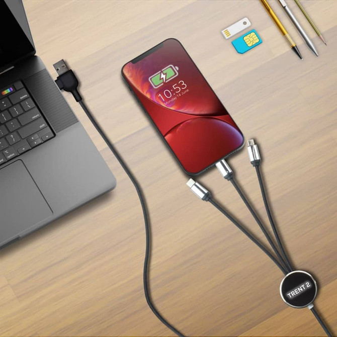 A charging cable with three connectors (USB-C, Lightning, Micro-USB) connected to a phone and a laptop, on a wooden surface.