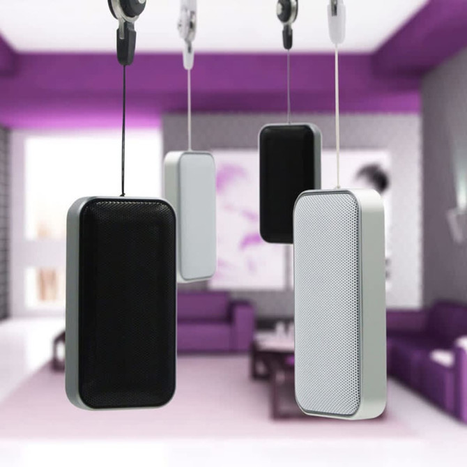 A set of Nano Lite Bluetooth speakers in black and white, suspended in a stylish interior setting.