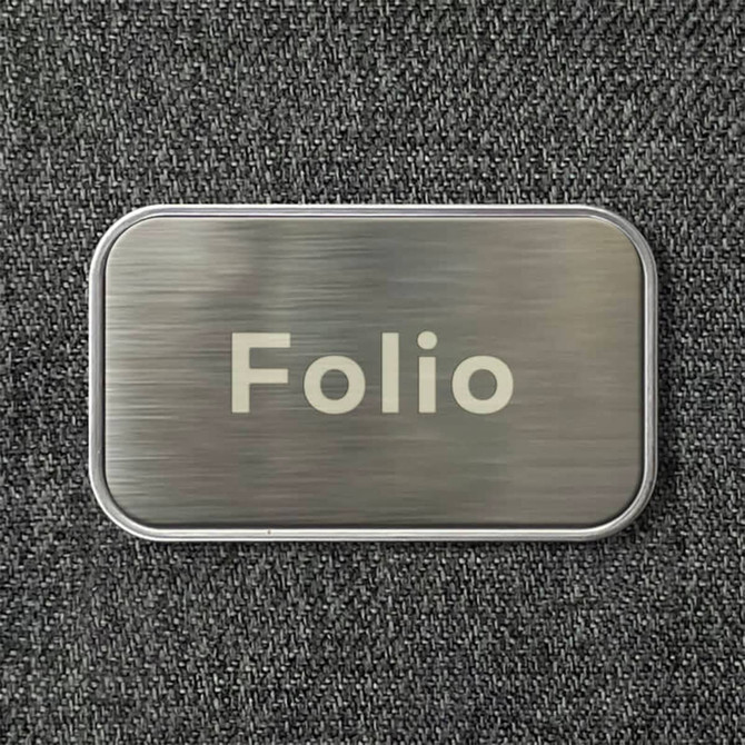 A metallic rectangular tag with the word "Folio" engraved on a textured grey background.