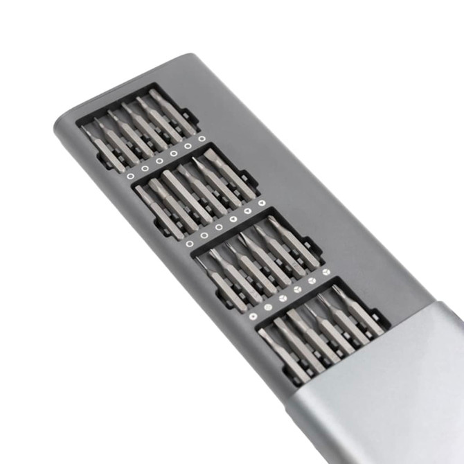 A precision tool kit with multiple interchangeable screwdriver bits in a sleek grey case and a small branding logo.