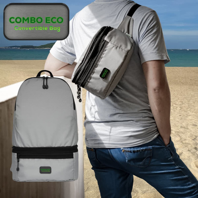 A grey, convertible bum bag is worn over the shoulder, alongside a grey backpack, against a beach backdrop.