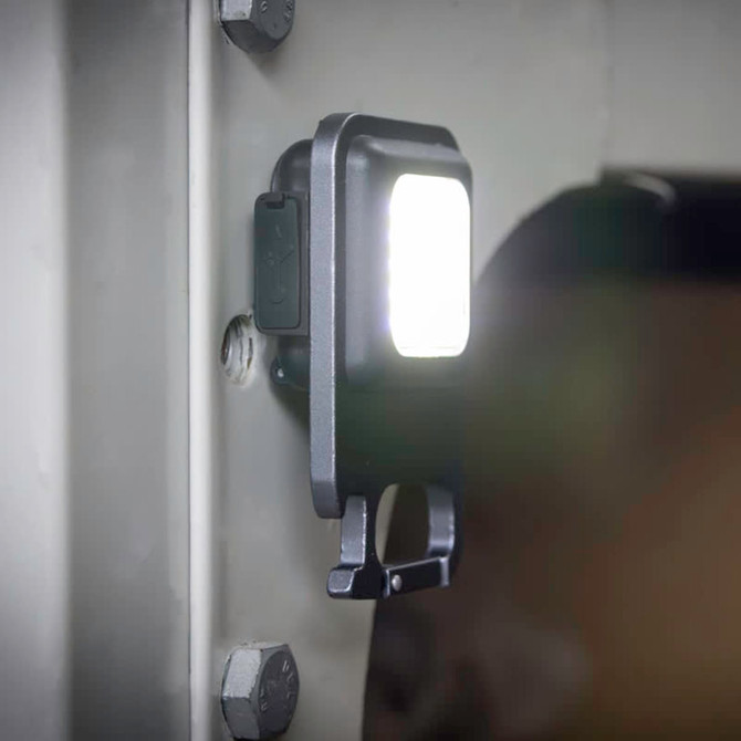 A black multi-tool with a COB LED light attached to a metal surface, featuring a compact design and a functional clip.