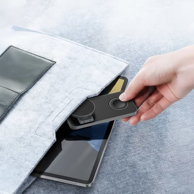 A grey 15W 3-in-1 magnetic wireless charging station being taken from a pocket, with a tablet visible below. A grey 15W 3-in-1 magnetic wireless charging station being taken from a pocket, with a tablet visible below.
