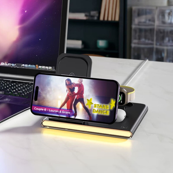 A wireless charger in black with a smartphone, earbuds, and a USB adaptor, set on a desk beside a laptop. A wireless charger in black with a smartphone, earbuds, and a USB adaptor, set on a desk beside a laptop.
