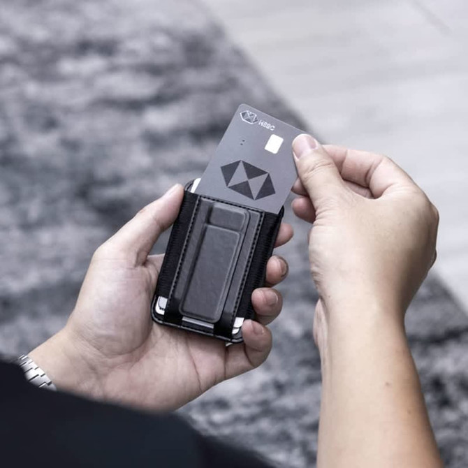 A black wallet with a card in hand, featuring a sleek design and metal accents.