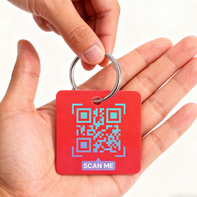 A red custom shape plastic card key tag held in a hand, featuring a QR code and a metal keyring.