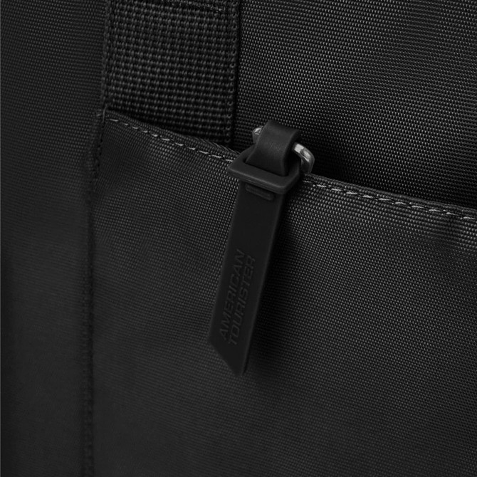 A close-up of a black tote bag featuring textured fabric and a zippered pocket with a pull tab.