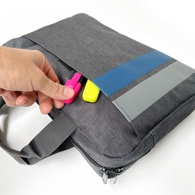 A grey satchel with a zip closure and a front pocket, featuring pink and yellow highlighters inserted.