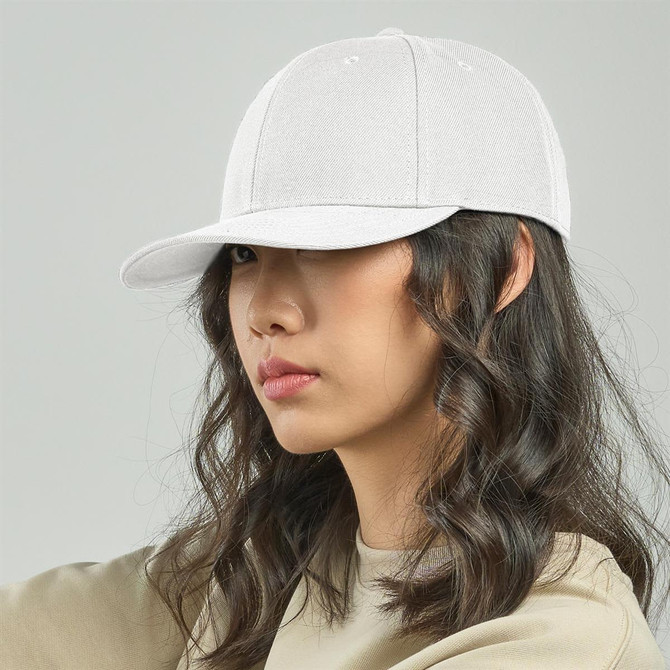 A white cap is worn by a person with wavy hair, featuring a structured brim and a logo on the front.