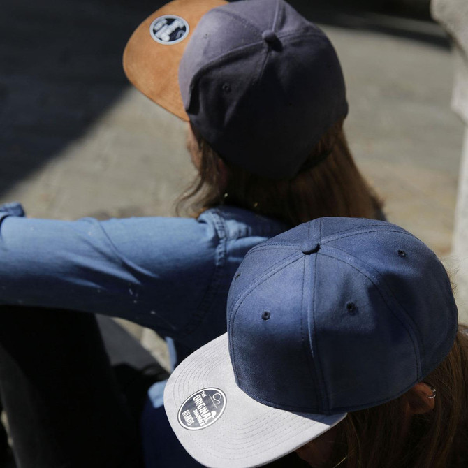 Two caps in navy and brown tones, featuring contrasting brims and a logo on each.