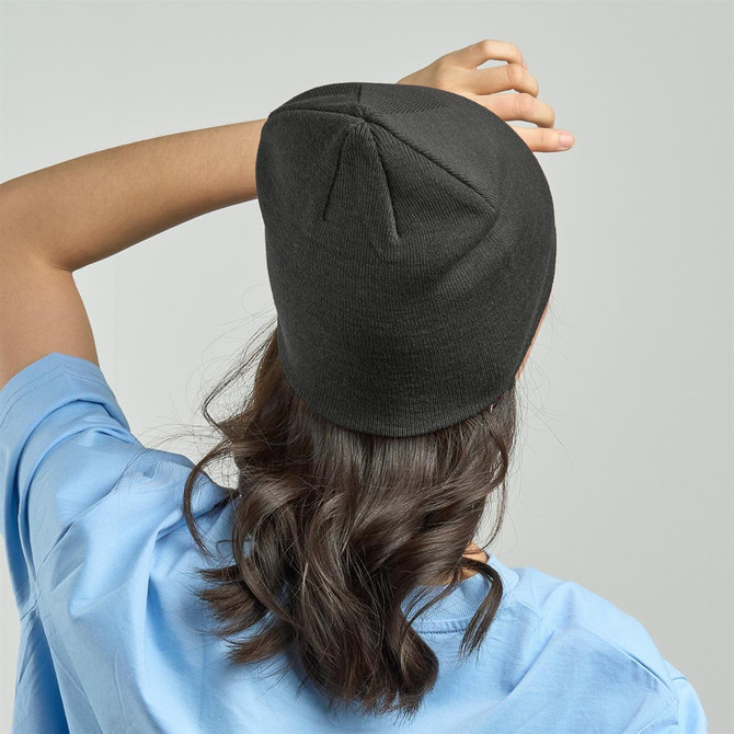A black beanie styled on a person’s head, with their hair cascading down their back.