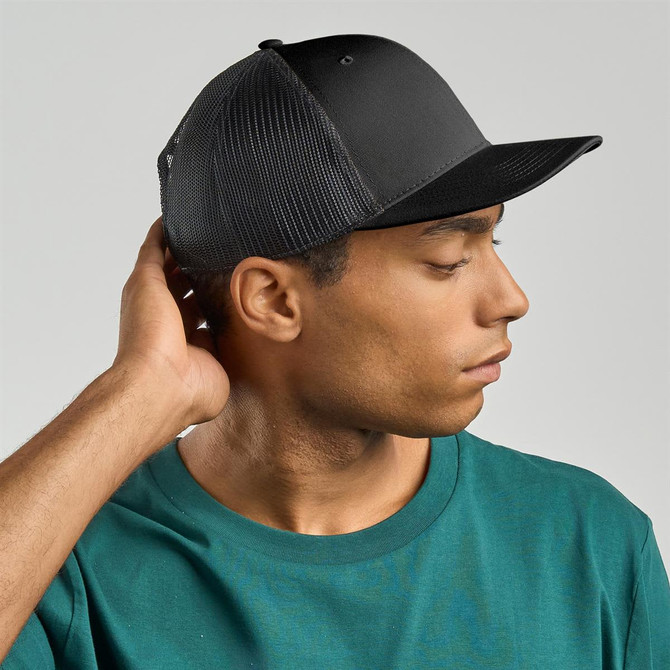 A black trucker cap with mesh sides, worn by a person with short hair, set against a neutral background.