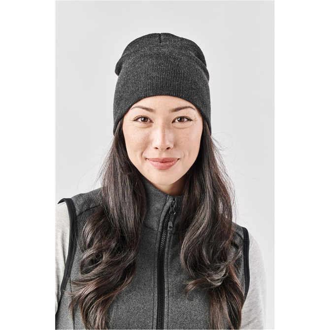 A dark grey knit beanie worn by a woman with long hair, smiling against a light background.