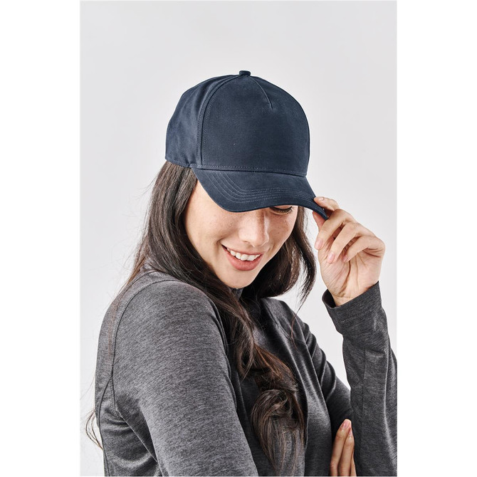 A navy cap featuring a structured design and a logo, worn by a smiling woman in a grey top.