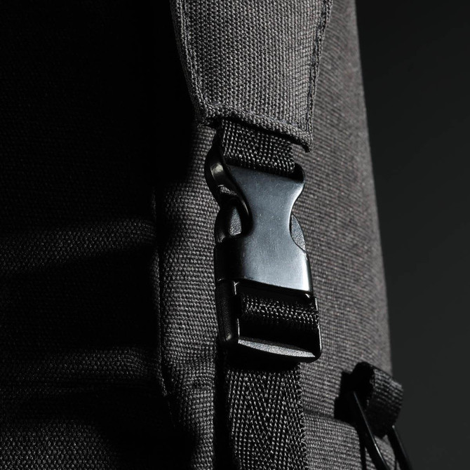 A close-up of a black duffle bag strap featuring a plastic clip fastener and textured fabric.