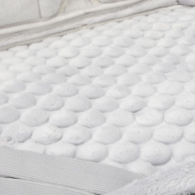 A soft, textured surface featuring white fluffy material with raised round patterns.