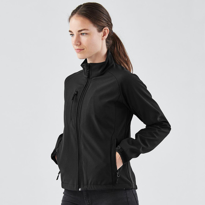 A woman is wearing a black ultra-light shell jacket, featuring a zippered front and side pockets.