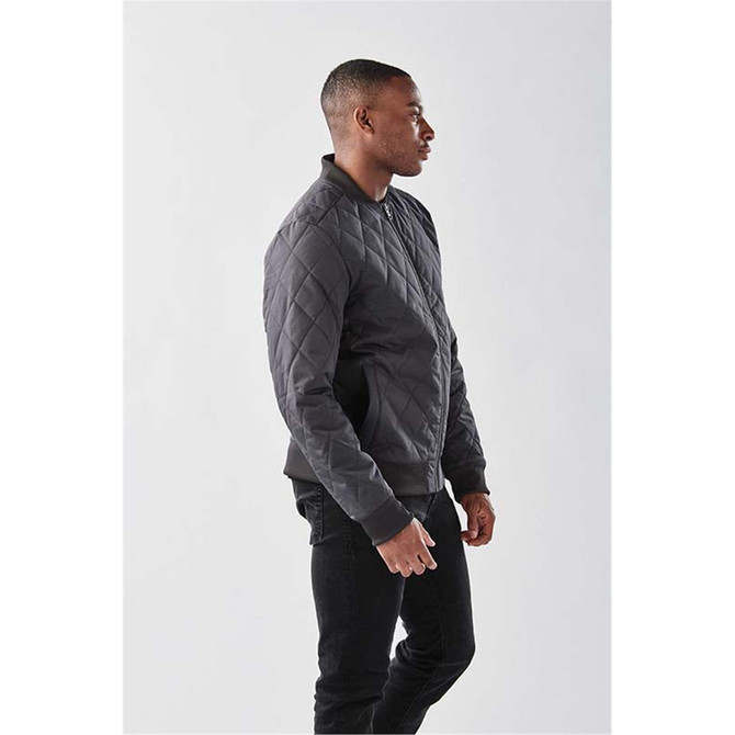 A man's thermal jacket in dark grey with a quilted design, featuring a logo and a relaxed fit.