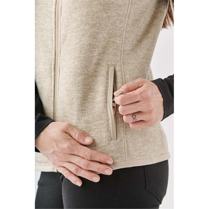 A light khaki women's fleece vest featuring a zip pocket and a smooth texture, modelled by a woman.