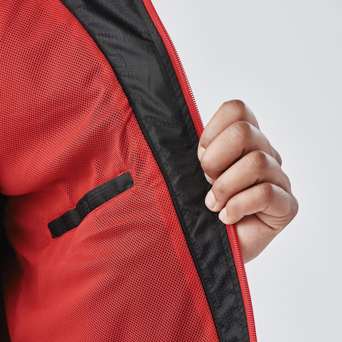 A close-up of a red jacket with a black lining, featuring a hand holding the zipper area. The jacket has a logo.