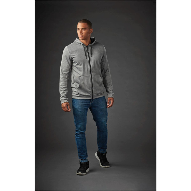 A grey hoodie with a zip and pockets, worn by a man, paired with blue jeans and black sneakers.