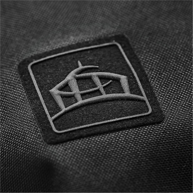 A close-up of a black jacket featuring a textured logo patch. The fabric has a durable finish.