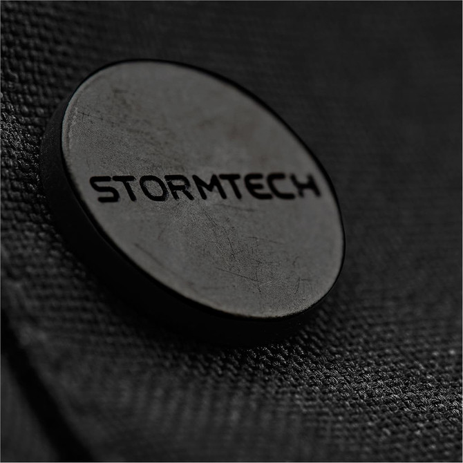 A close-up of a dark textured fabric featuring a circular black logo with the word "STORMTECH."