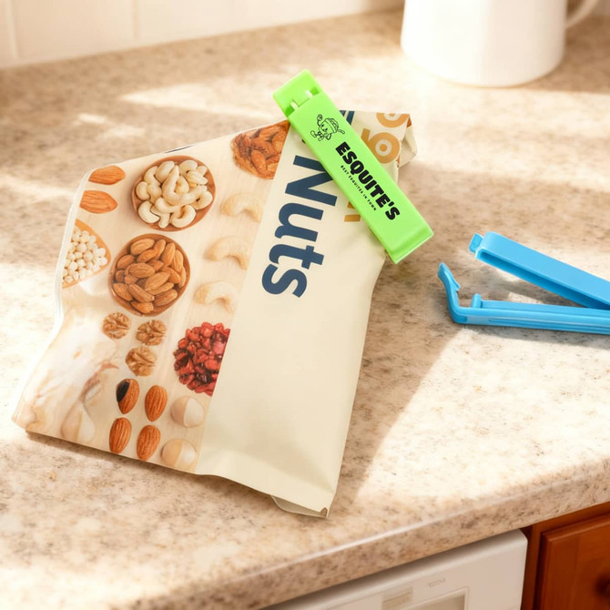 A green clip secures a bag of mixed nuts on a countertop, alongside a blue seal clip.