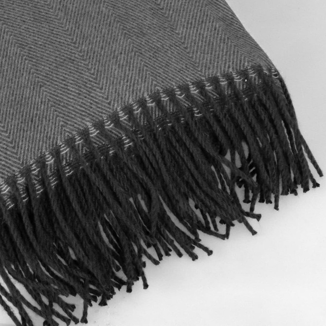 A grey herringbone throw blanket with decorative fringes along one edge, featuring a subtle texture.