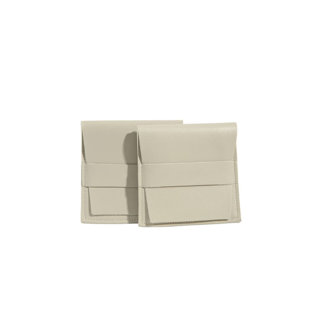 A duo of beige PU leather flip jewelry pouches with a sleek design and a simple strap closure.