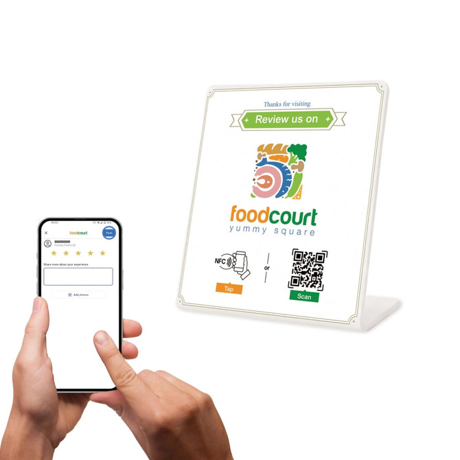 A smartphone held in a hand next to a white NFC Review Stand displaying a logo and QR code.