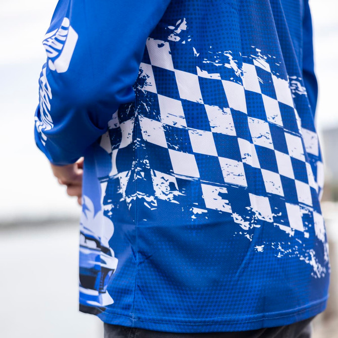 A long sleeve fishing polo in blue with a checkered pattern and abstract design. It features a logo on the sleeve.