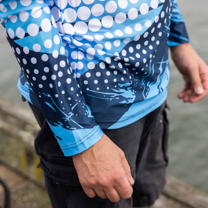 A long sleeve fishing tee featuring a blue and white dot pattern and abstract design, with a visible logo.