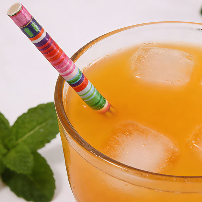 A drink bottle filled with orange liquid and ice, featuring a colourful striped 4-ply paper straw and mint leaves.
