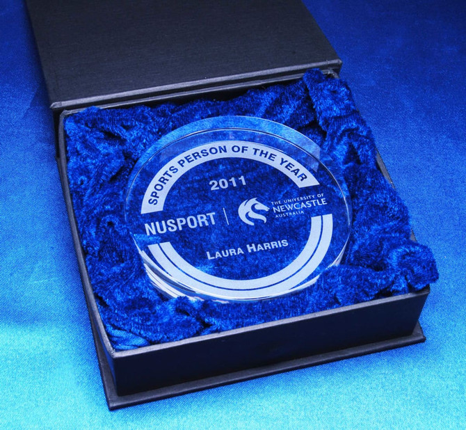 A crystal medallion in a black presentation box, surrounded by blue cushioning material.