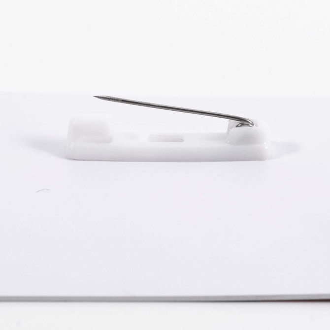 A white PVC name badge with a safety pin attachment on the back.