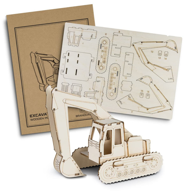 A wooden model of an excavator in a natural finish alongside its assembly instructions on a kraft background.