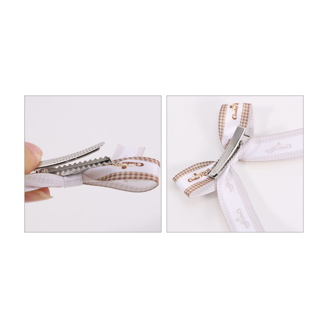 A hair clip bow with a white and brown patterned ribbon and a silver clip. The design features a double loop.