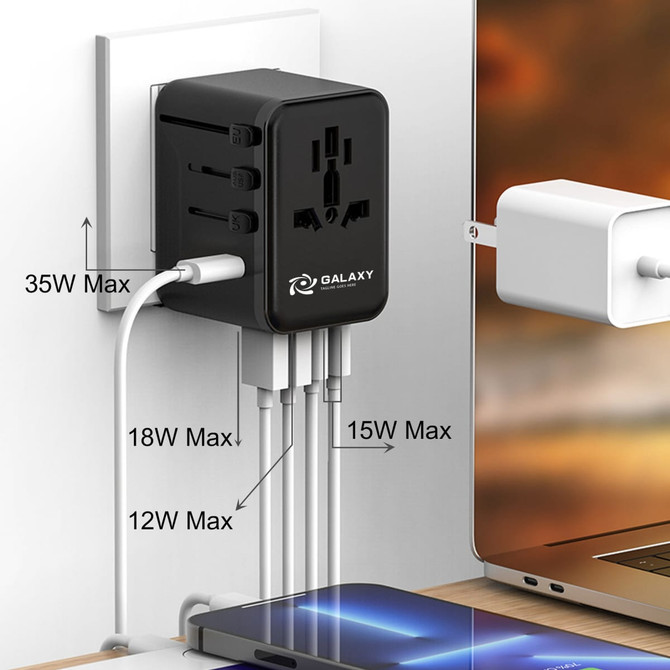 A black 35W GaN universal travel adapter with multiple ports, plugged into a wall outlet and connected to devices.