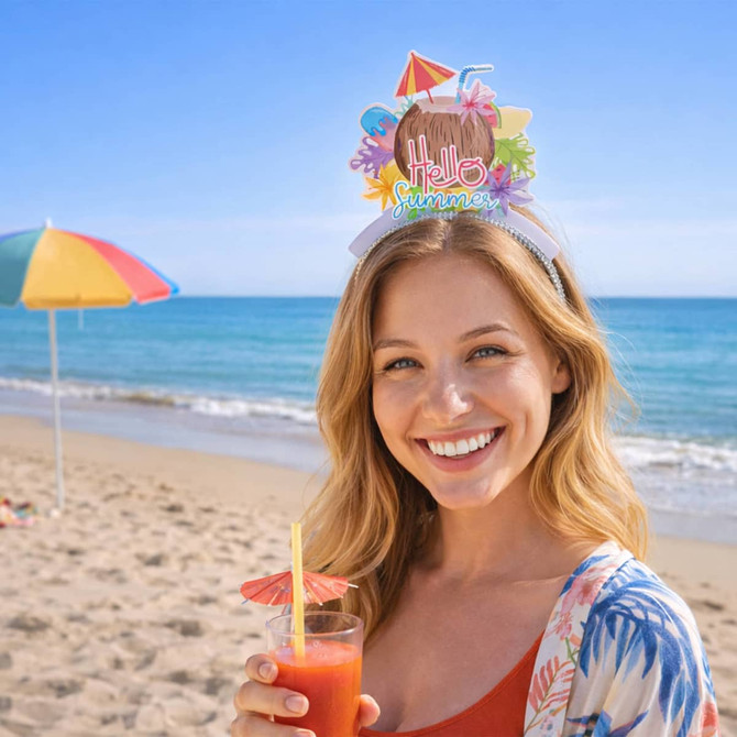 A woman at the beach wears a colourful headband with a decorative topper while holding a drink.