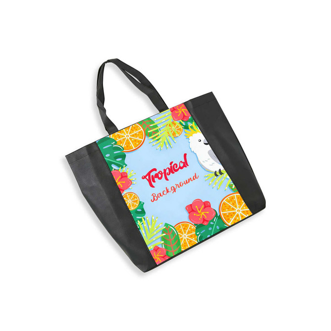 A tote bag in black featuring a full-colour tropical design with flowers, fruit, and a parrot illustration.