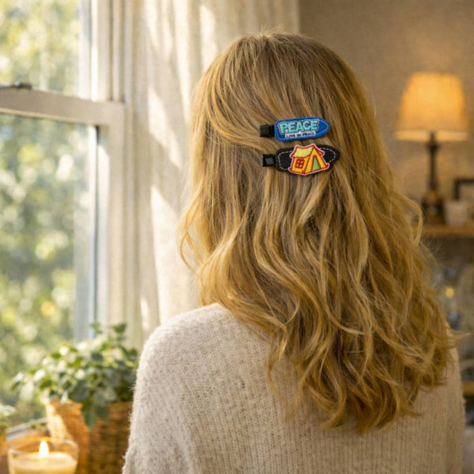 A denim duck bill hair clip in blue and red, showcasing patch designs, worn in wavy hair by a person.